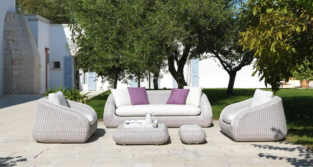 phorma armchair in lighter grey shades out in the open with the garden trees in the background