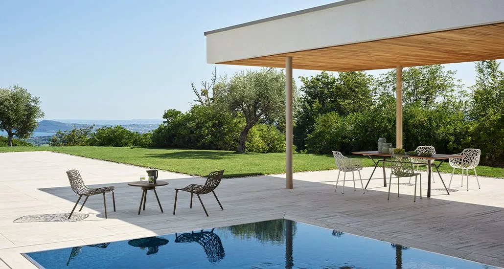 a contemporary outdoor pool area featuring sleek chairs and tables, creating a stylish and inviting ambiance