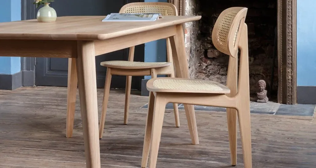 the titus dining chair in natural varnished oak and cane seat around an oak finished wooden dining table