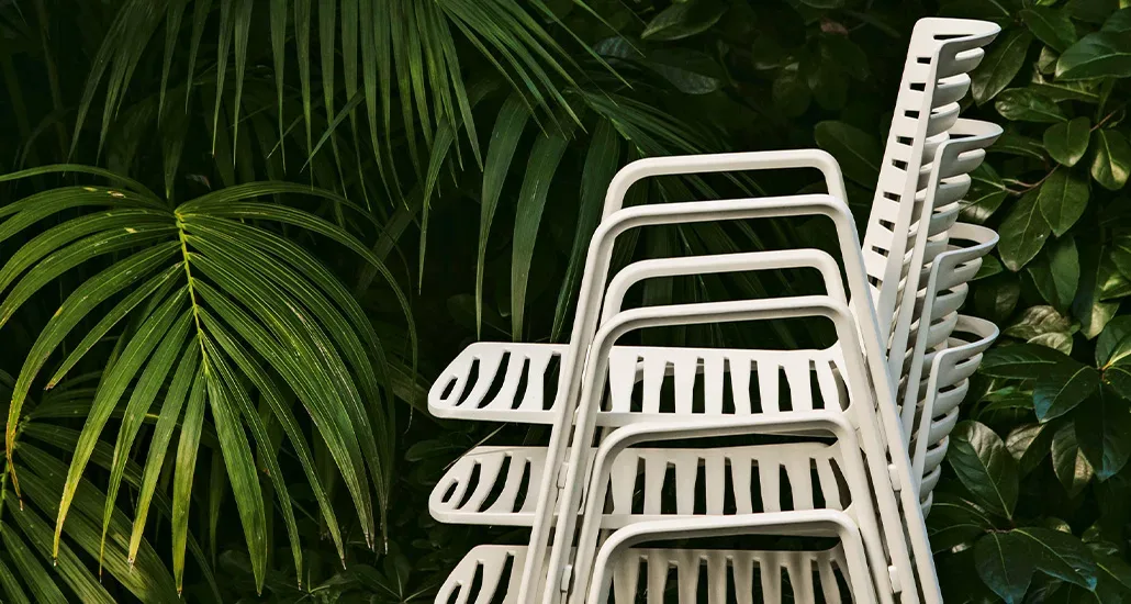 the zebra chair with armrest by fast is the perfect outdoor seating solution, here we see it in white against some dark green palm leave making the perfect wallpaper picture.