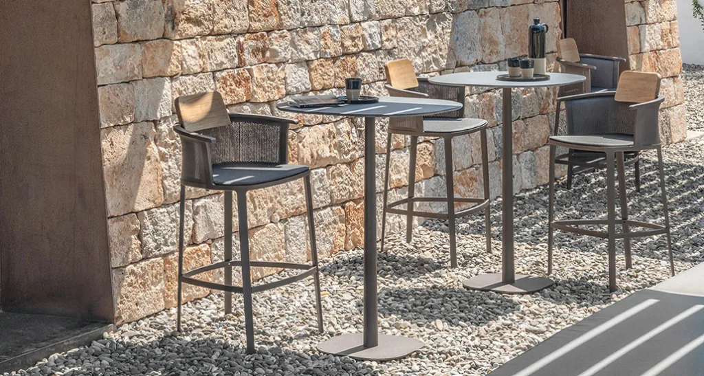 nicolette bar stool is a contemporary outdoor bar stool with aluminium and teak structure and fabric back and seat. nicolette is suitable for hospitality and contract projects.