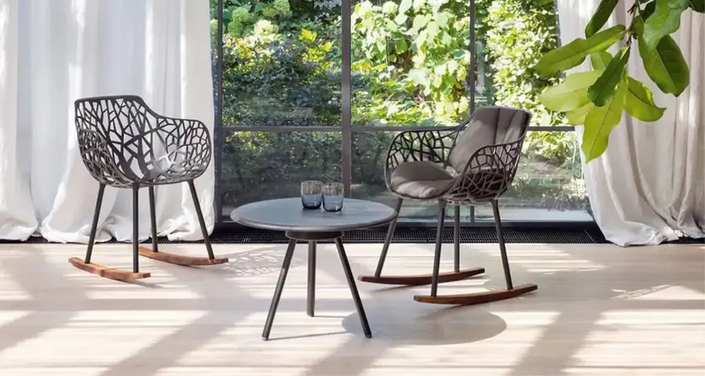 Forest Rocking Armchair is contemporary outdoor rocking armchair with aluminium frame and wood base and is placed in a contract hospitality outdoor space.