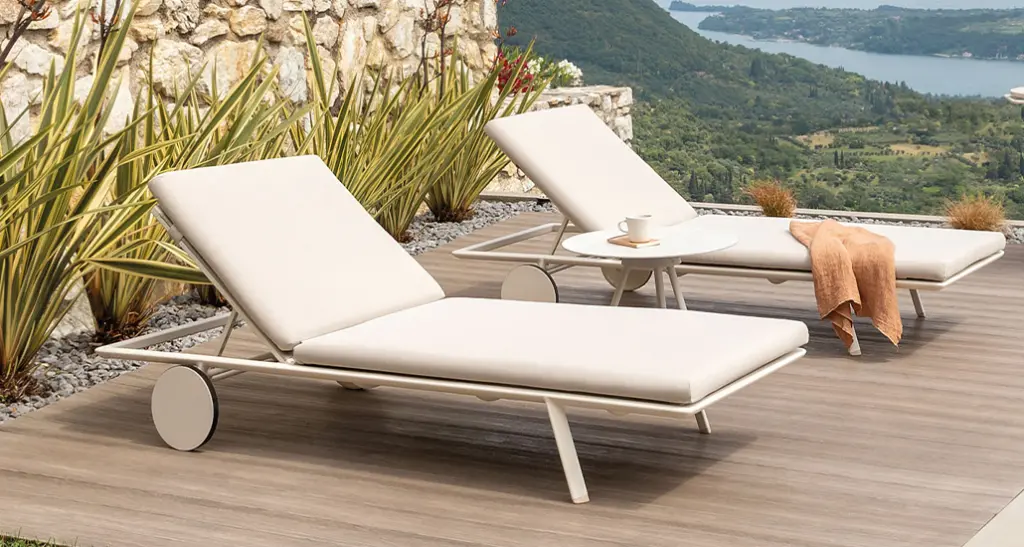 zebra sunlounger is a contemporary outdoor sunlounger with aluminium frame and is suitable for hospitality and contract spaces. zebra is placed here in outdoor patio with a beautiful background with sea and green hills.
